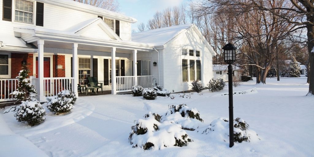 A house with snow-covered shrubs and walkways.