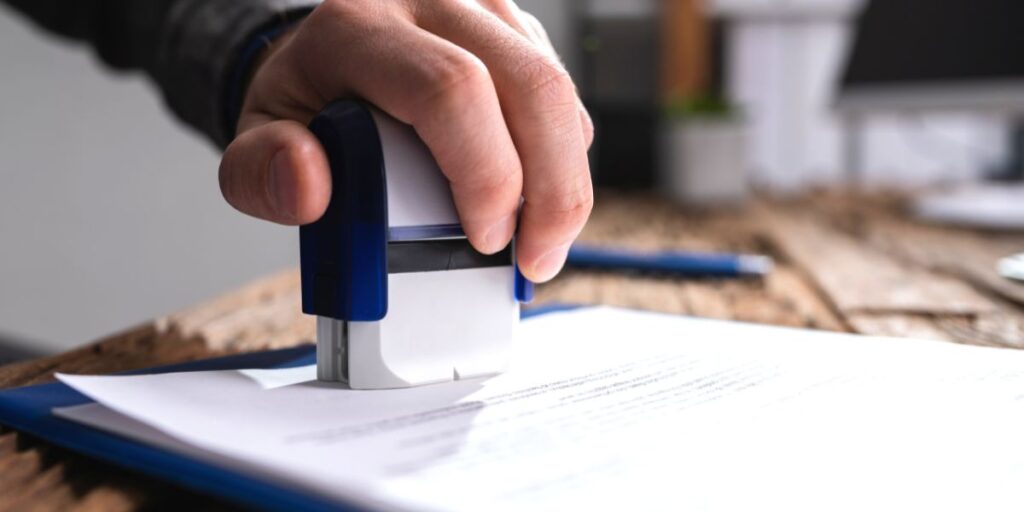 A hand stamps an official document.