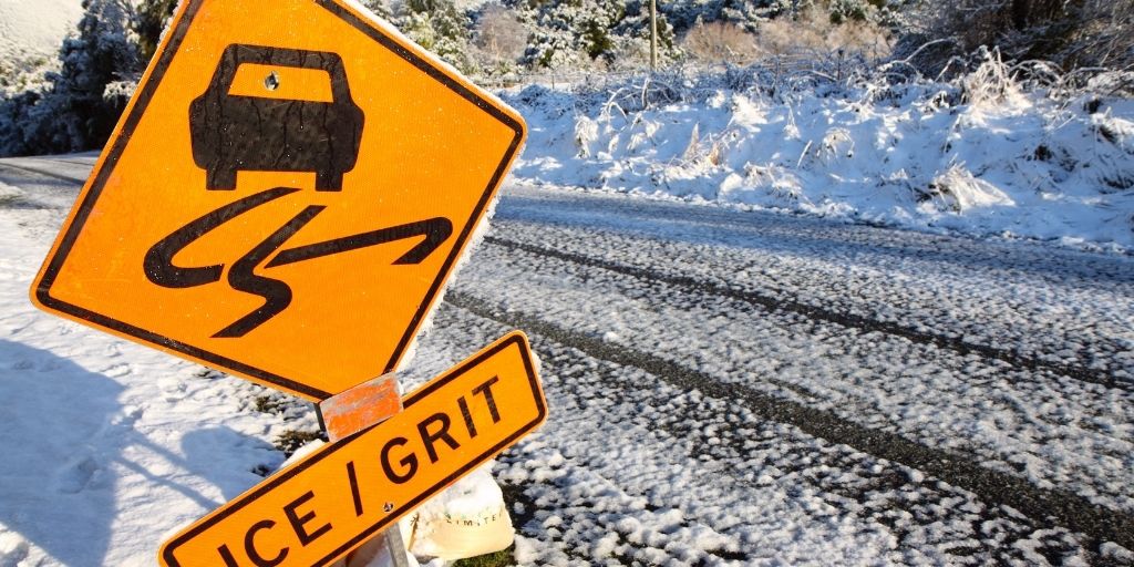 snow covered road with warning sign