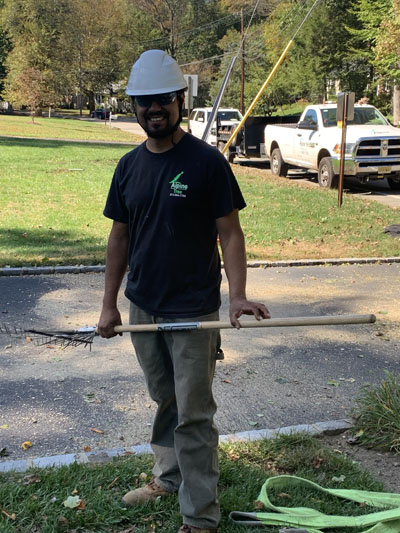 An Alpine Tree Service employee holds a rake for cleanup of a New Jersey yard