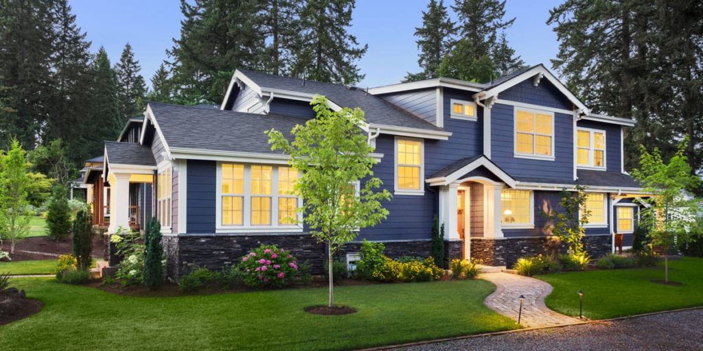 newly-planted trees in a lawn in front of a house